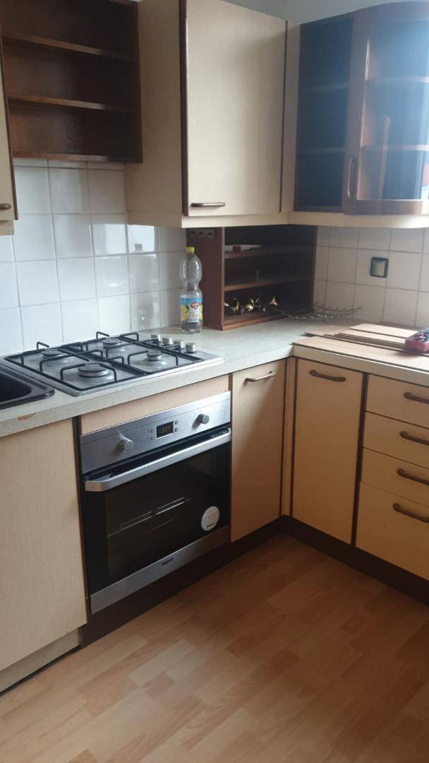 Küche mit Gasherd, Backofen und beigen Einbauschränken.