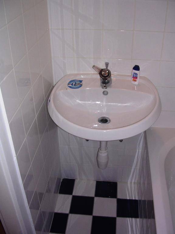 Badezimmer mit Waschbecken und Badewanne, gefliest in Schwarz-Weiß.