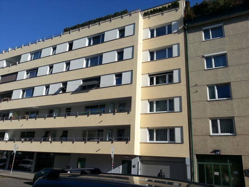 Detailansicht der Fassade eines Wohngebäudes mit mehreren Balkonen und Fensterläden.