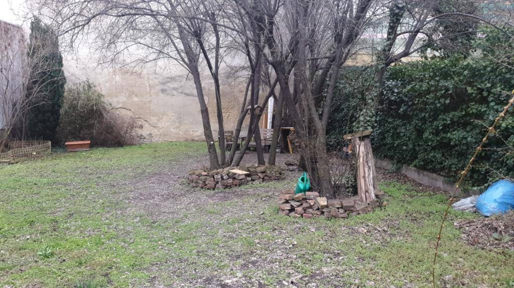 Gepflegter Garten mit Bäumen, Rasen und einer gemütlichen Sitzecke, ideal zur Entspannung.