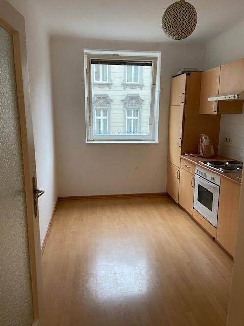 Helle Küche mit Einbaumöbeln, Parkettboden und Fensterblick auf die Stadt.