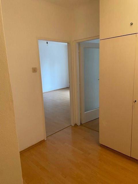 Flur mit Parkettboden und Zugang zu mehreren Zimmern, darunter ein Schlafzimmer.