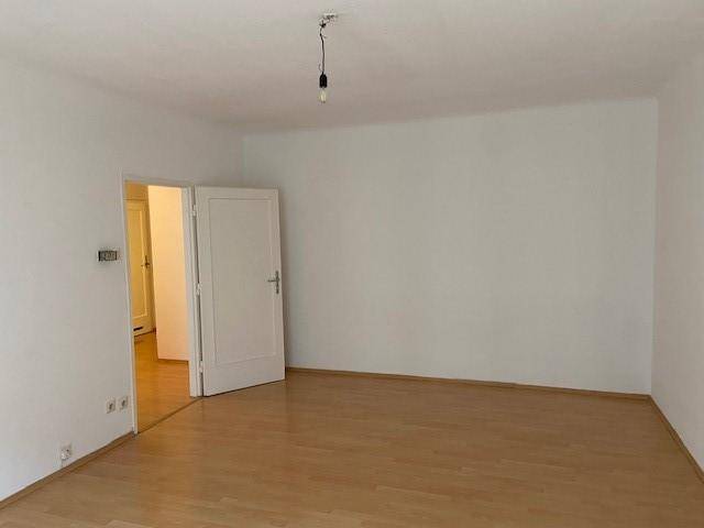 Leeres Zimmer mit Parkettboden und Zugang zu einem weiteren Raum.
