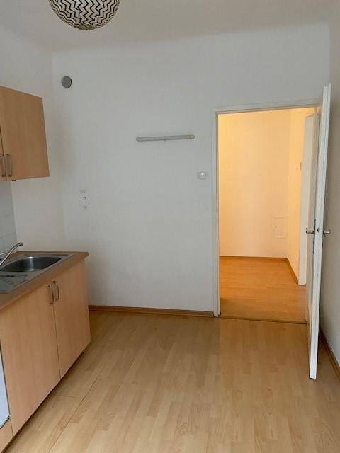 Küchenbereich mit Einbauschränken und Zugang zu einem weiteren Zimmer.