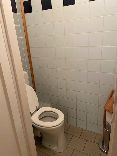 Separate Toilette mit hellblauen Fliesen und einem einfachen WC-Becken.