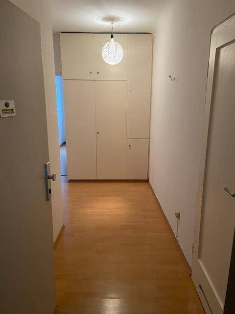 Heller Flur mit Holzfußboden und Einbauschränken, der zu weiteren Räumen führt.