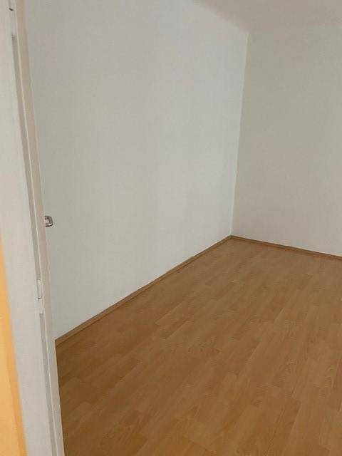 Leerer Raum mit hellem Parkettboden und weißen Wänden, bereit zur individuellen Gestaltung.