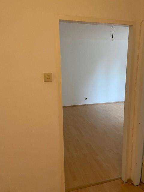 Heller Durchgangsbereich mit Parkettboden, der zu einem angrenzenden, leeren Zimmer führt.