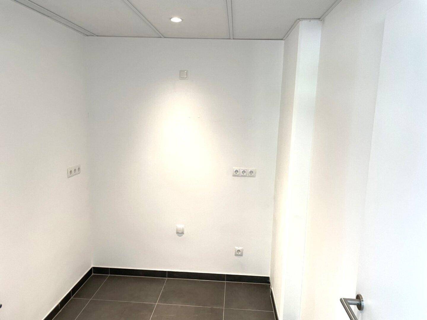 Kleiner Nebenraum mit dunklen Fliesen und mehreren Steckdosen, geeignet als WC oder Abstellraum.