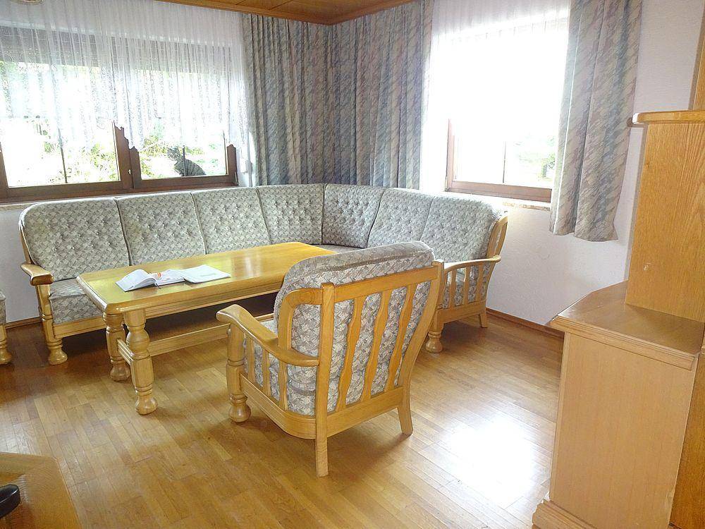 Geräumiges Wohnzimmer mit Holzparkett, bequemen Sofas und großen Fenstern für viel Tageslicht.