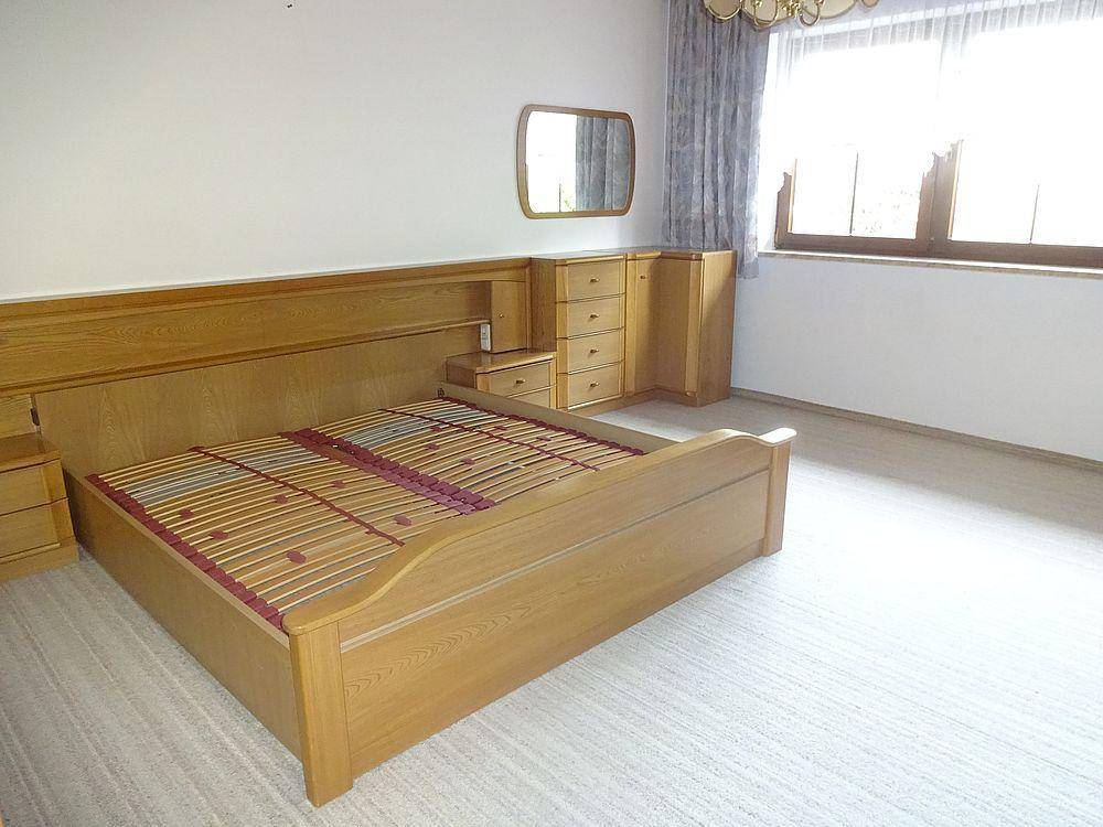 Helles Schlafzimmer mit Holzdoppelbett, passenden Nachttischen und einem großen Fenster.