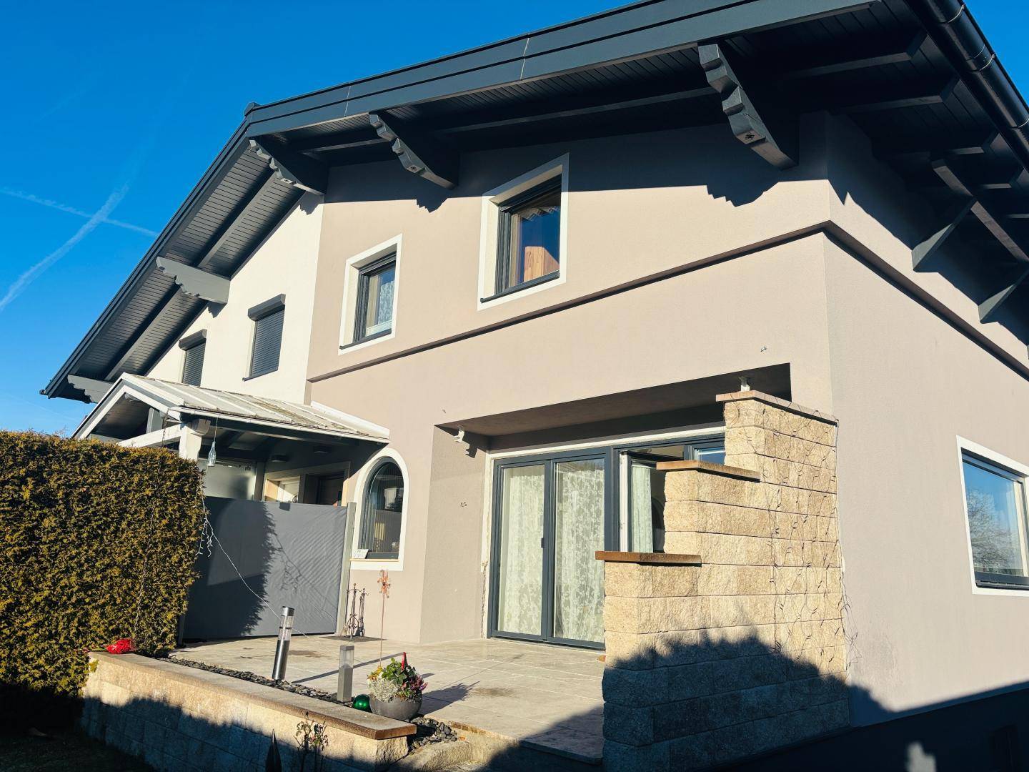 Außenansicht des Hauses mit gepflasterter Terrasse und gepflegter Hecke.