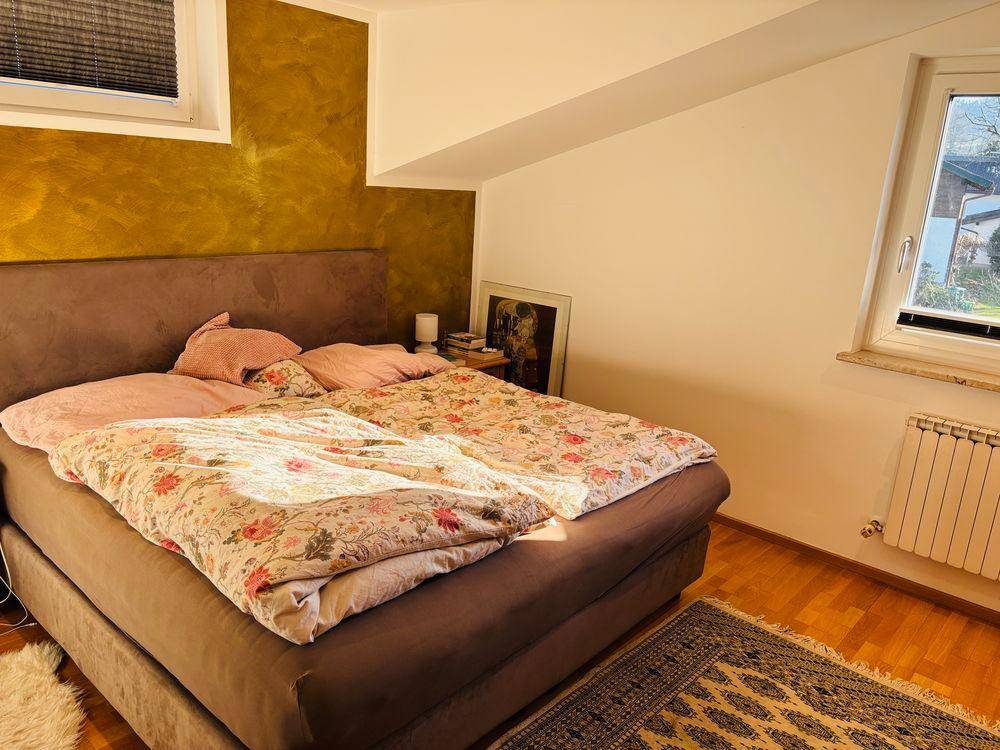 Gemütliches Schlafzimmer mit Doppelbett, Holzboden und Fenster mit Blick ins Grüne.