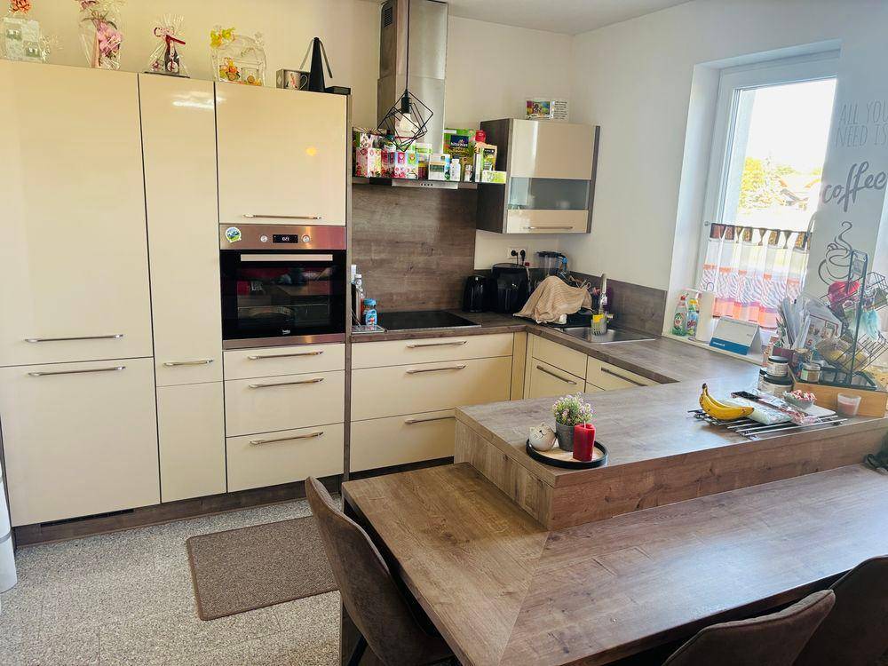 Moderne Küche mit cremefarbenen Schränken, integriertem Backofen und Induktionskochfeld.