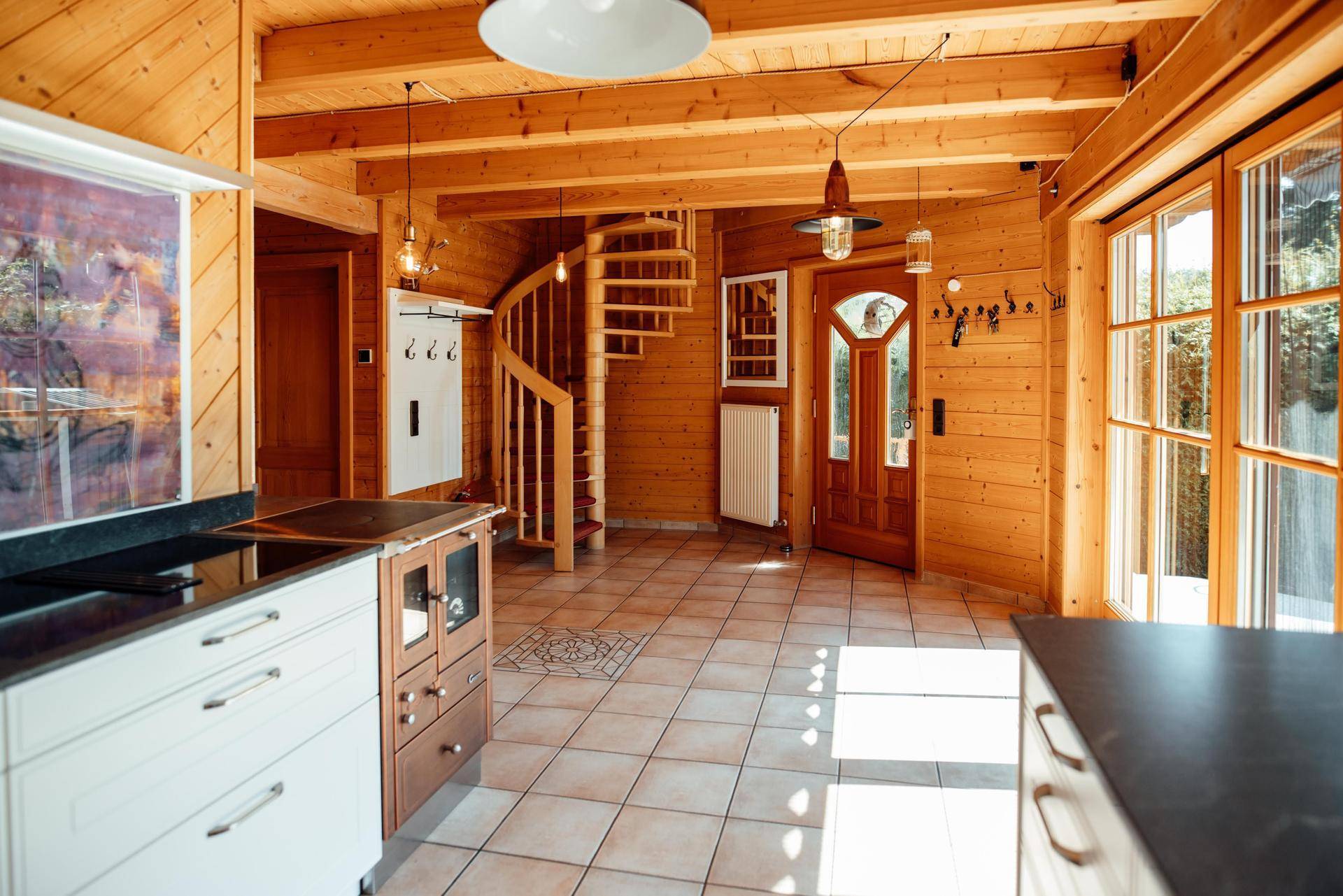 Offener Küchenbereich mit Fliesenboden, Holzvertäfelung und einer eleganten Wendeltreppe.