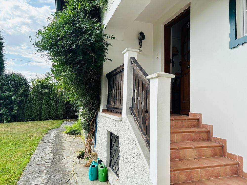 Eingangsbereich des Hauses mit gefliesten Stufen und einem gepflasterten Weg im Garten.