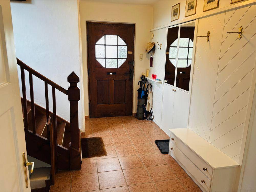 Gemütlicher Eingangsbereich mit Holztreppe, gefliestem Boden und traditioneller Einrichtung.