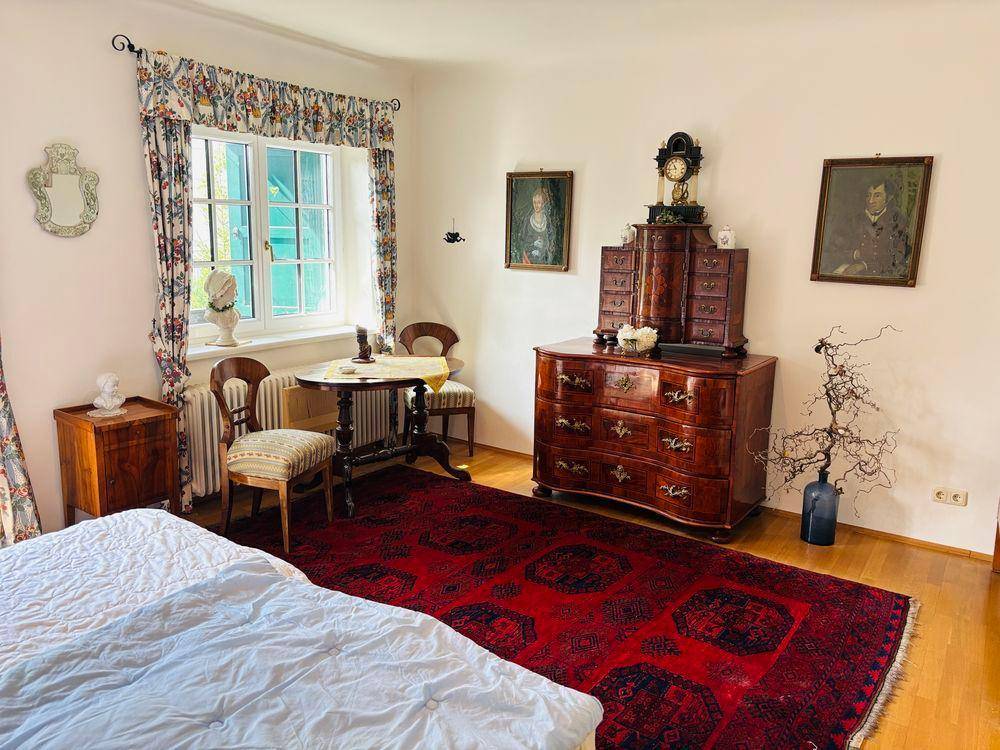Gemütliches Schlafzimmer mit Holzboden, traditionellen Möbeln und einem großen Teppich.