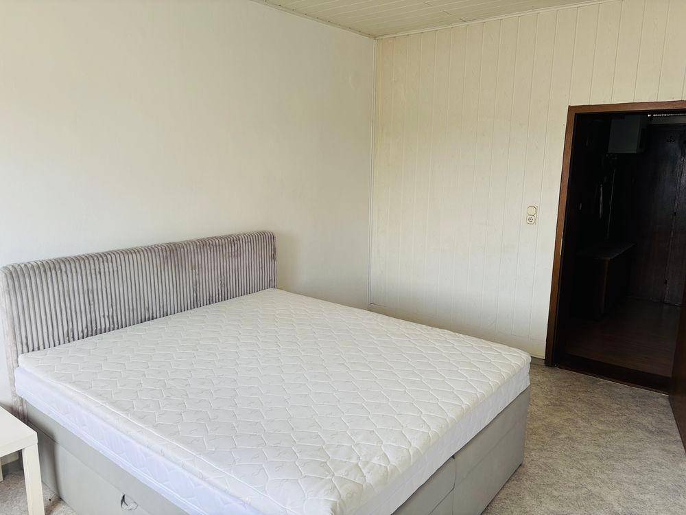 Schlafzimmer mit Doppelbett, weißen Wänden und holzgetäfelter Decke.