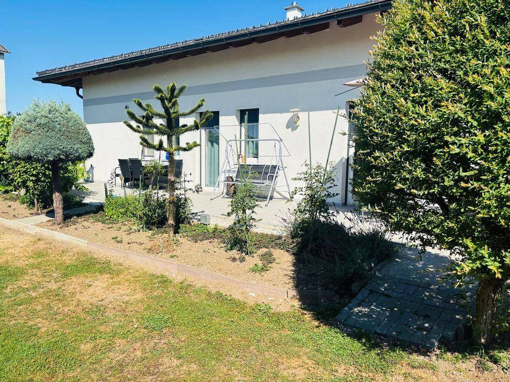 Sonniger Terrassenbereich mit Sitzgelegenheiten und Blick auf den gepflegten Garten.