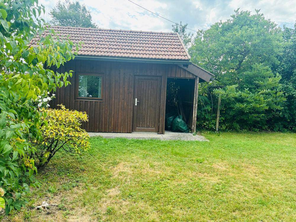 Rustikaler Holzschuppen mit Ziegeldach im hinteren Bereich des Gartens.