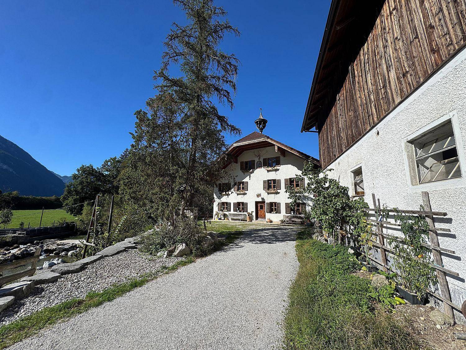 Weitläufiger Blick auf das traditionelle Bauernhaus und die umliegende grüne Landschaft.