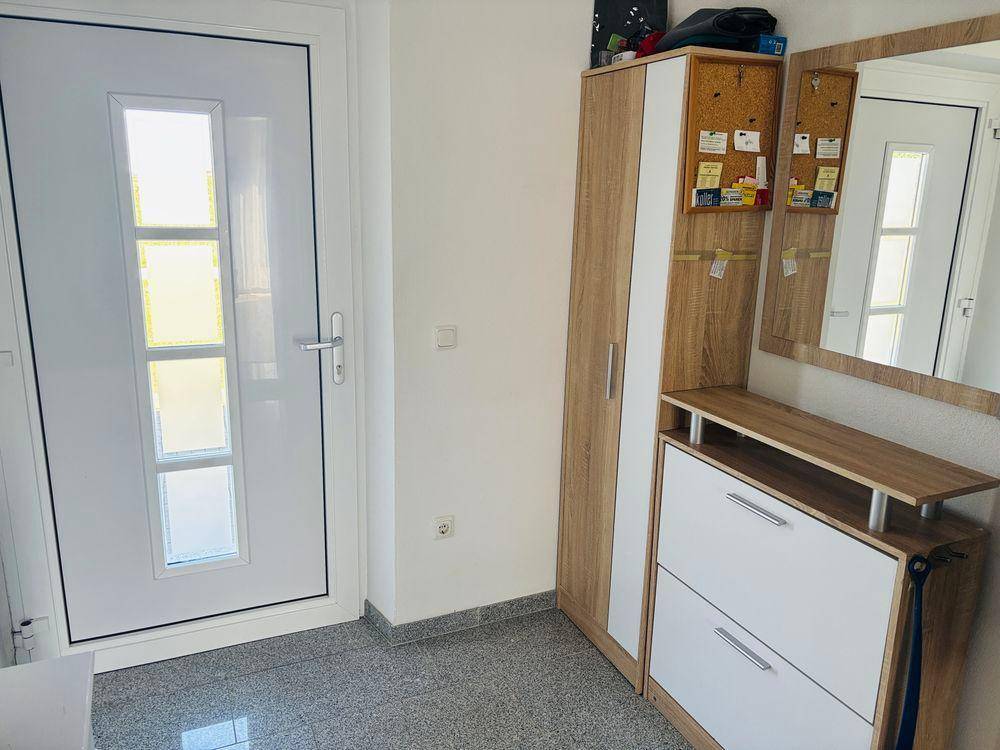 Heller Eingangsbereich mit moderner Haustür, praktischem Schuhschrank und großem Spiegel.