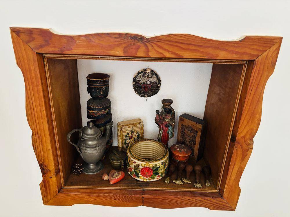 Dekorative Holznische mit traditionellen Figuren und Ziergegenständen an der Wand.
