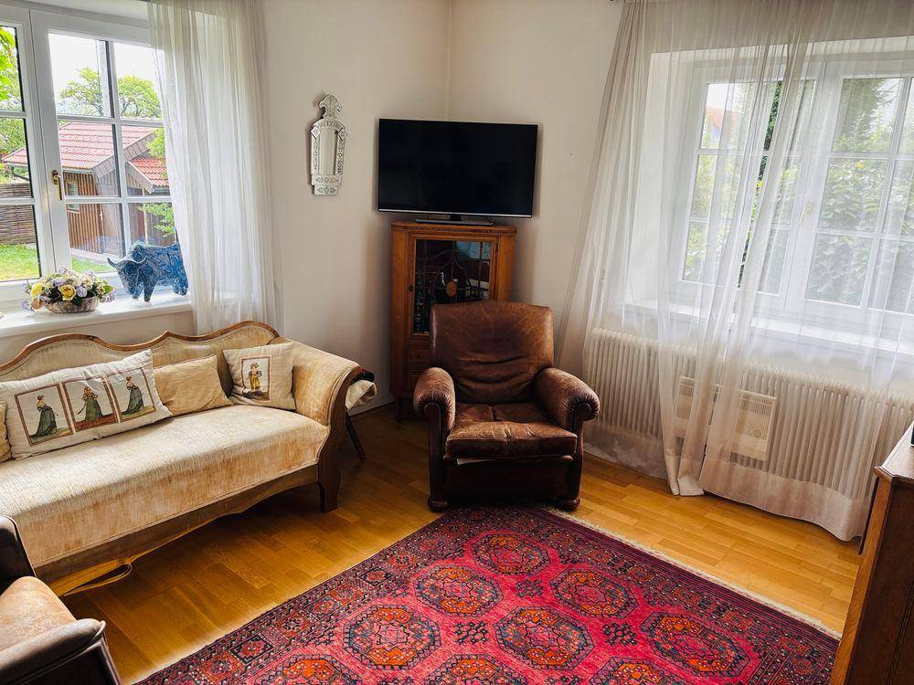 Helles Wohnzimmer mit Holzboden, bequemen Sofas und einem traditionellen Teppich.