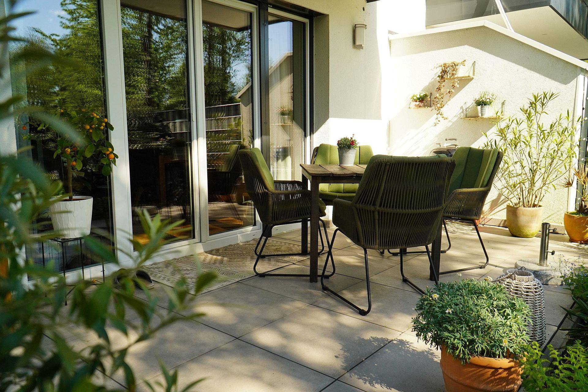 Gemütliche Terrasse mit modernen Gartenmöbeln und großen Glasfronten zum Innenbereich.