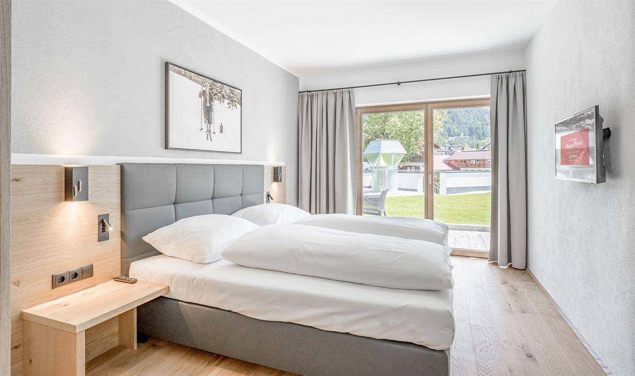 Gemütliches Schlafzimmer mit Doppelbett, Holzboden und direktem Zugang zum Garten.