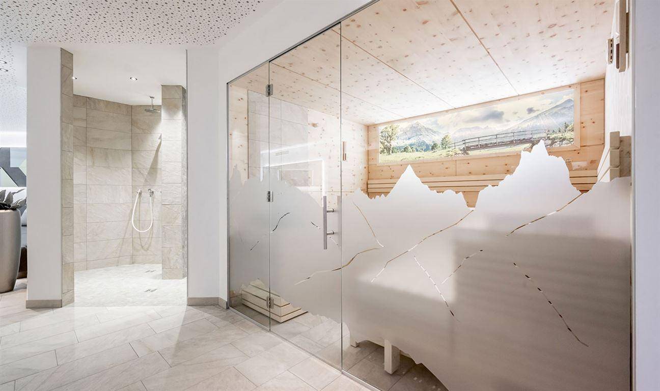 Moderner Wellnessbereich mit Sauna und großzügiger Duschkabine, gestaltet im Alpenstil.