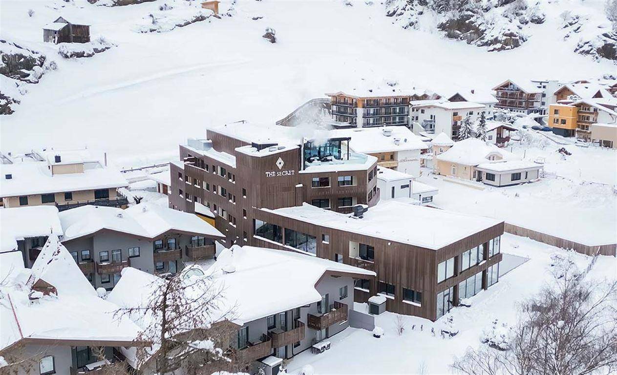 Panoramablick aus der Luft auf das moderne Hotelgebäude und die umliegenden Häuser im Schnee.