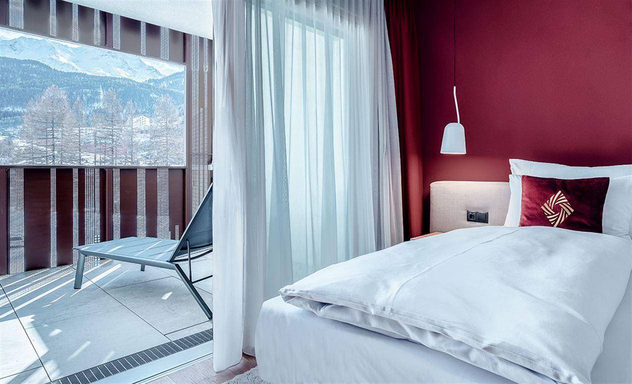 Helles Schlafzimmer mit Balkonzugang und Panoramablick auf die verschneiten Berge.