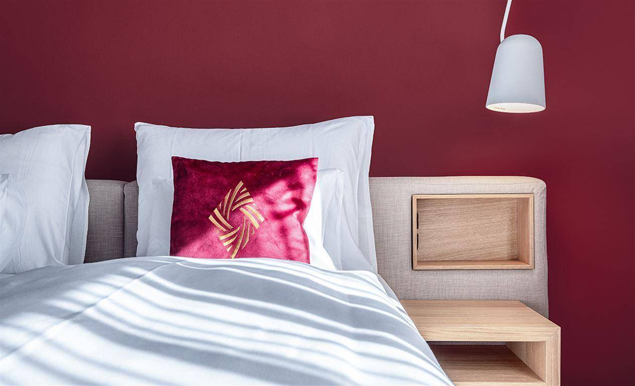 Detailansicht des Bettes mit roten Kissen und integriertem Nachttisch in modernem Schlafzimmer.