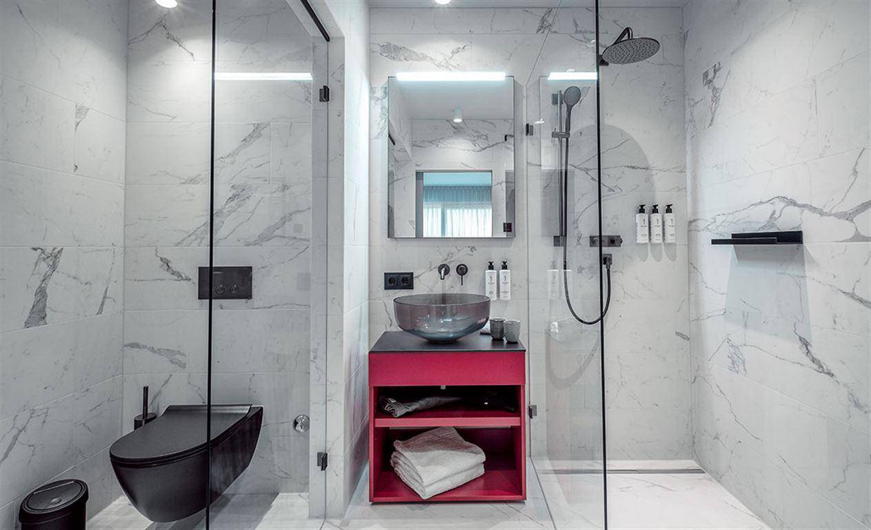 Luxuriöses Badezimmer mit Marmorfliesen, begehbarer Dusche und modernem Wand-WC.