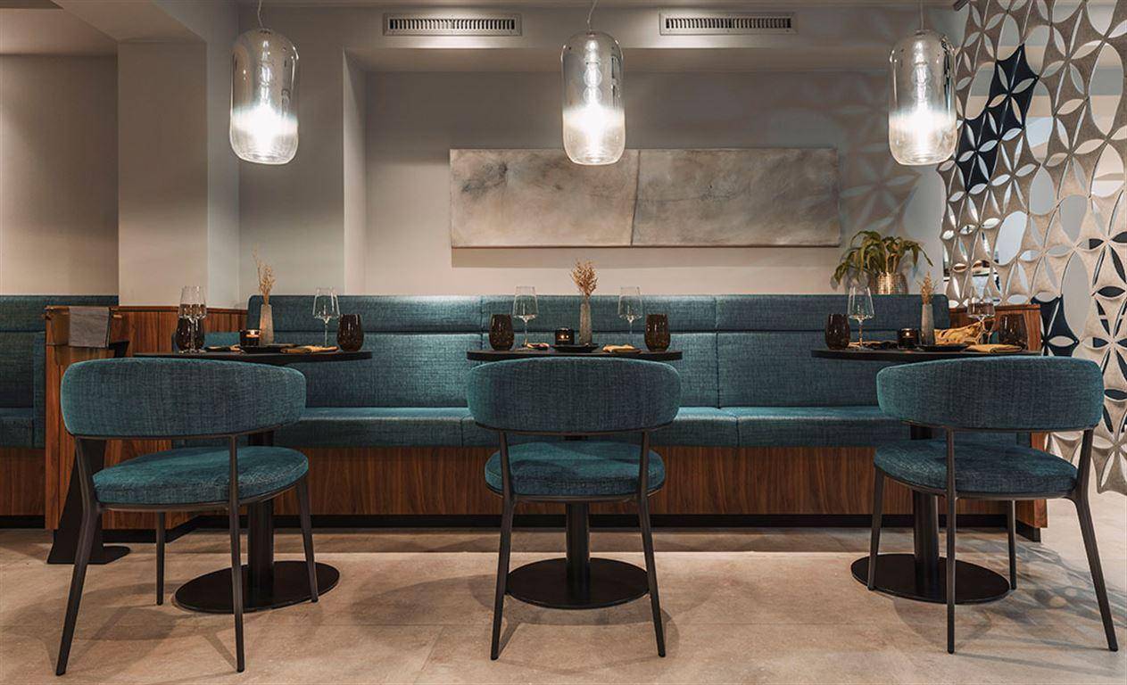 Detailansicht des Restaurantbereichs mit blauen Sitzbänken und modernen Pendelleuchten.