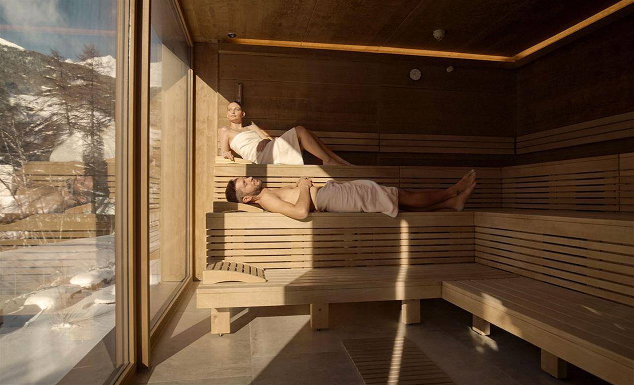 Helle Sauna mit Holzvertäfelung und großen Fenstern, die einen Blick nach draußen bieten.