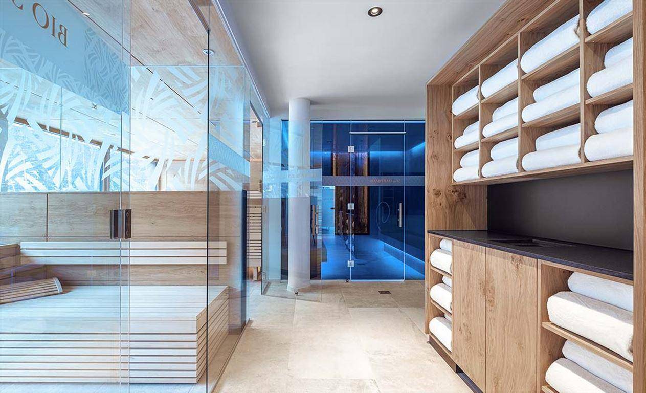 Heller Wellnessbereich mit Sauna, Holzregalen und Zugang zu weiteren Entspannungsbereichen.