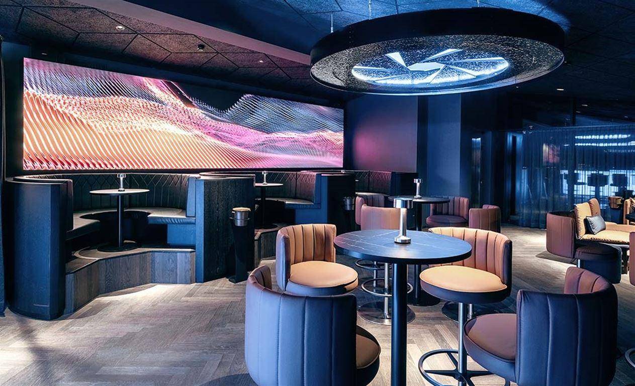 Moderner Loungebereich mit bequemen Sitzgelegenheiten und großer digitaler Kunstwand.