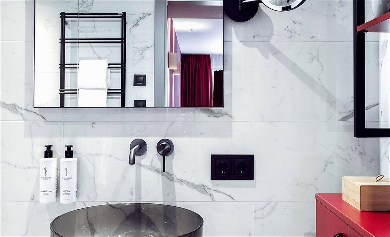 Modernes Badezimmer mit Marmorfliesen, stilvollem Waschbecken und beheiztem Handtuchhalter.