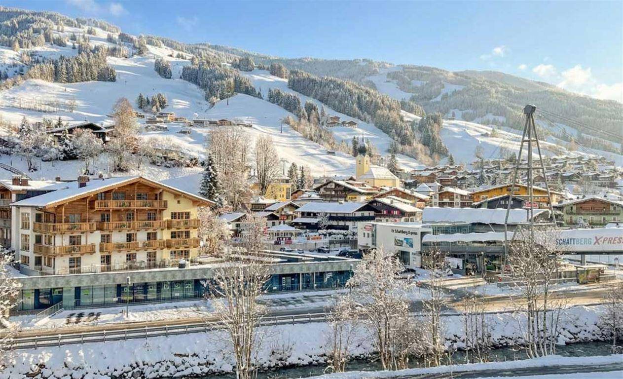 Panoramablick auf ein schneebedecktes Bergdorf mit traditionellen Gebäuden und Skiliften.