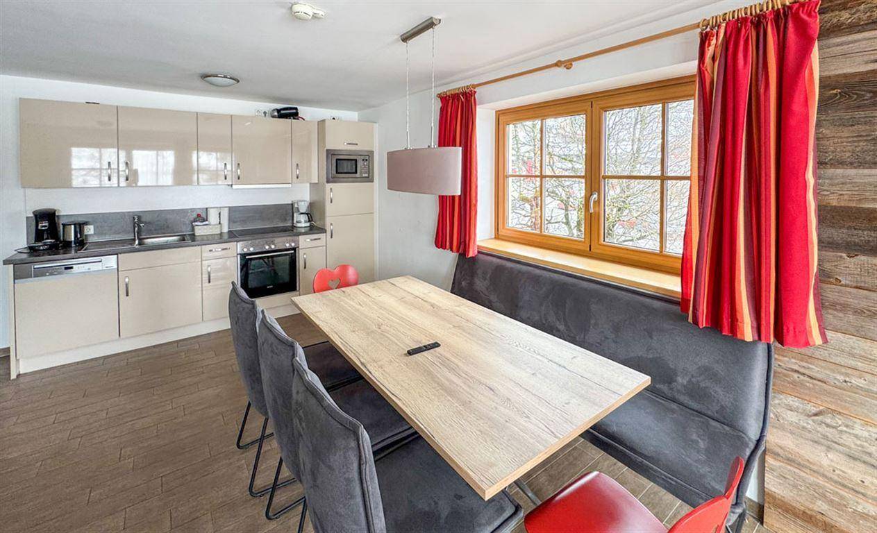 Moderne Küchenzeile mit Essbereich, Holztisch und Blick nach draußen durch das Fenster.