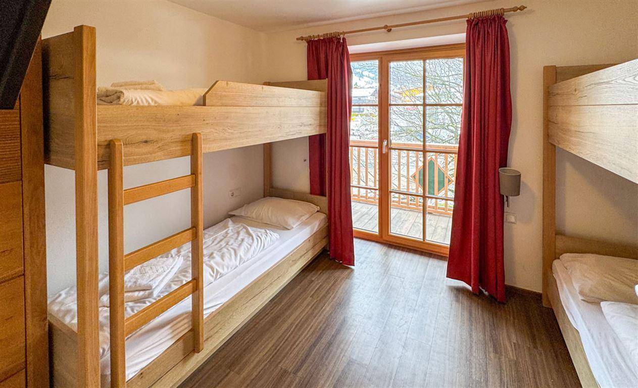 Kinderzimmer mit Etagenbetten, Holzboden und Balkonzugang, ideal für Familien.