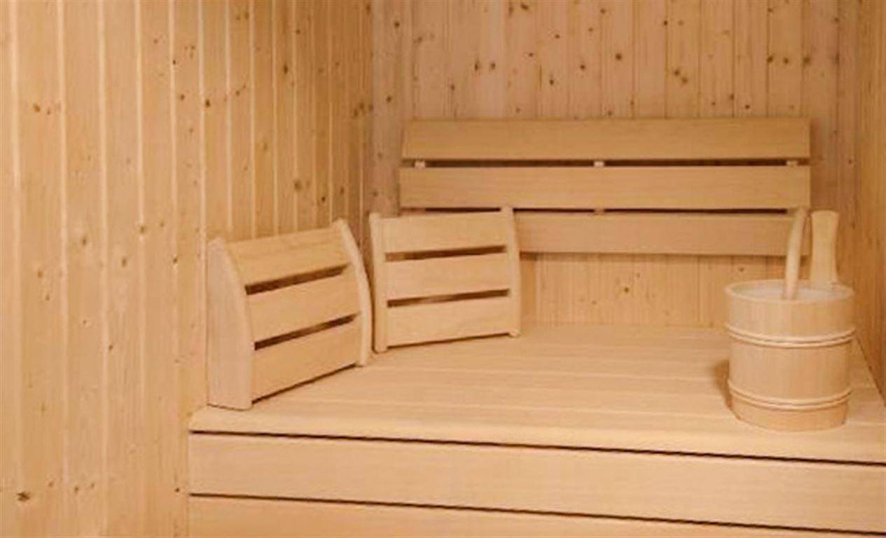 Gemütliche Holzsauna mit Bänken und traditionellem Aufgusseimer für Entspannung.