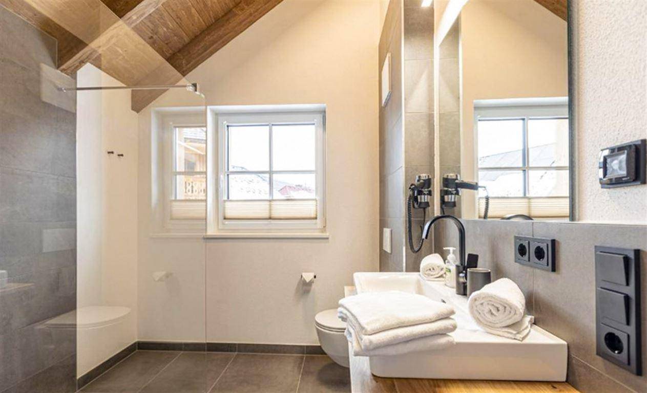 Modernes Badezimmer mit begehbarer Dusche, Doppelwaschbecken und Fenster.