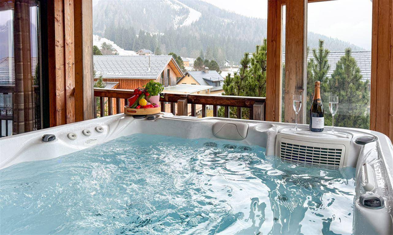 Whirlpool auf dem Balkon mit Sekt und atemberaubendem Blick auf die verschneiten Berge.