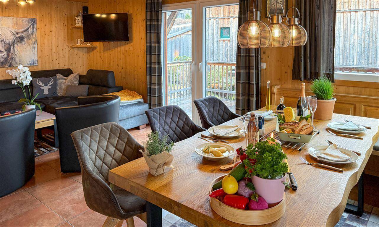 Rustikaler Essbereich mit großem Holztisch und gemütlicher Sitzecke im Hintergrund.