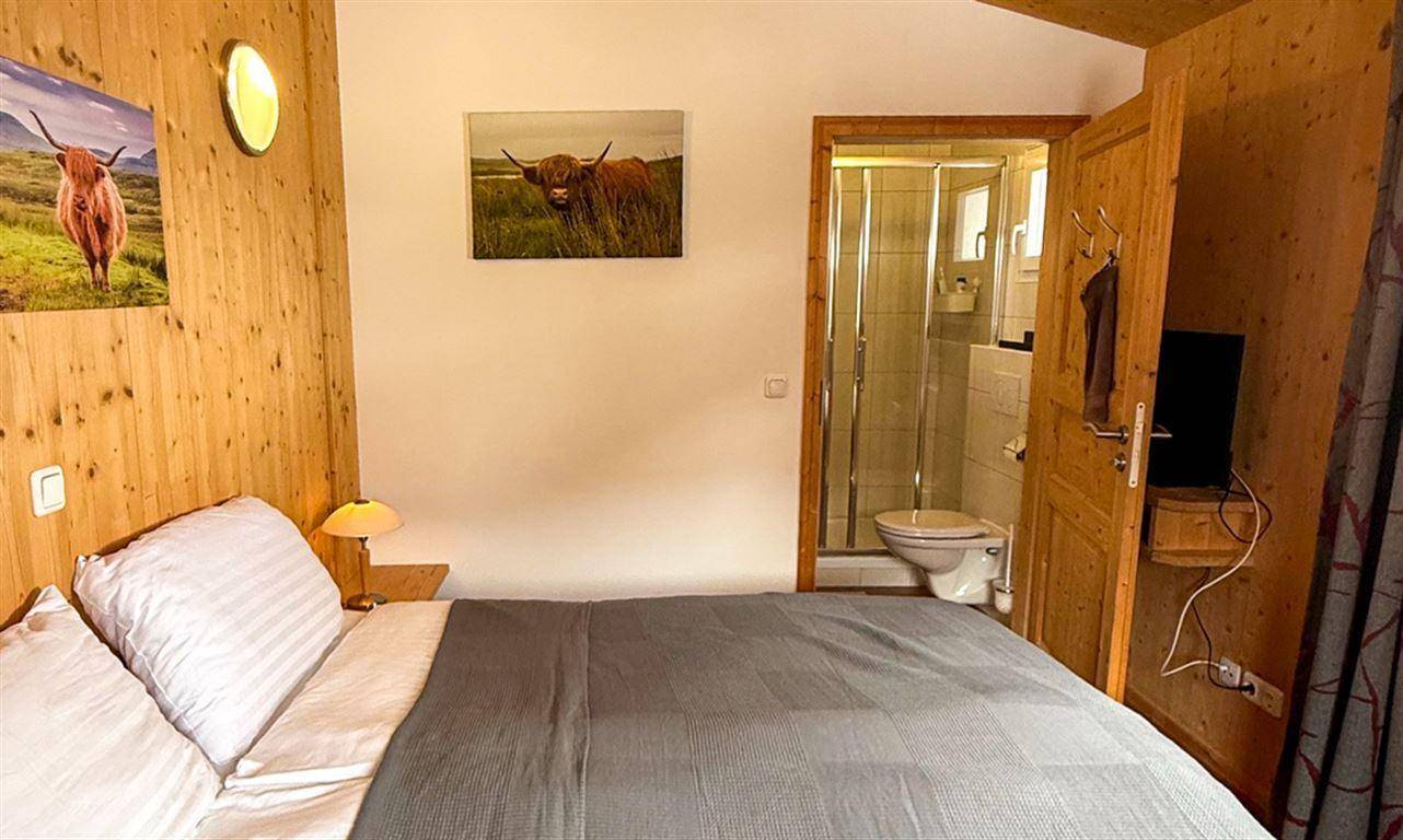 Schlafzimmer mit Holzwänden und direktem Zugang zu einem eigenen Badezimmer.