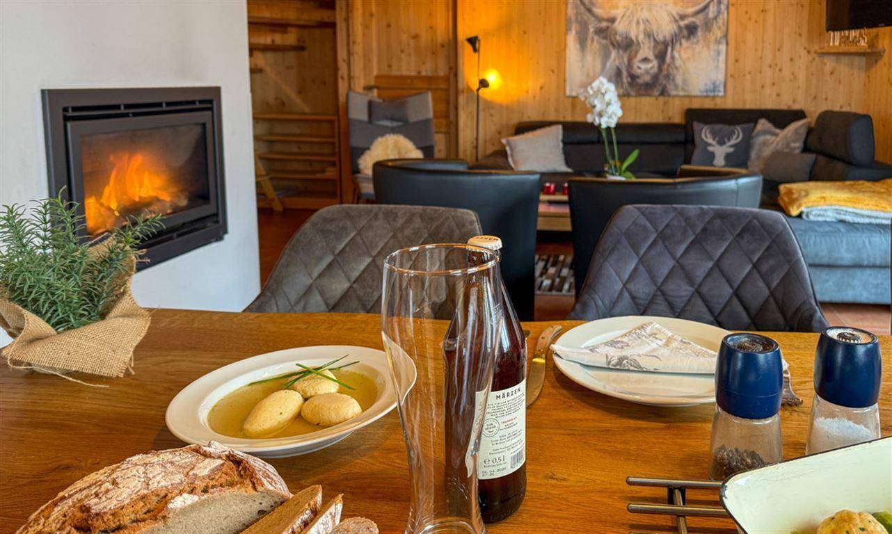 Gemütlicher Essbereich mit Kamin und Blick auf den Wohnbereich mit Sofa.